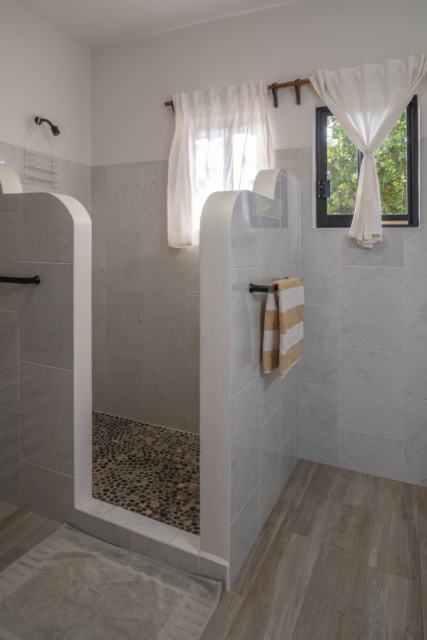 Walk-in shower at Casa Nisha with river-stone floor and marble tile