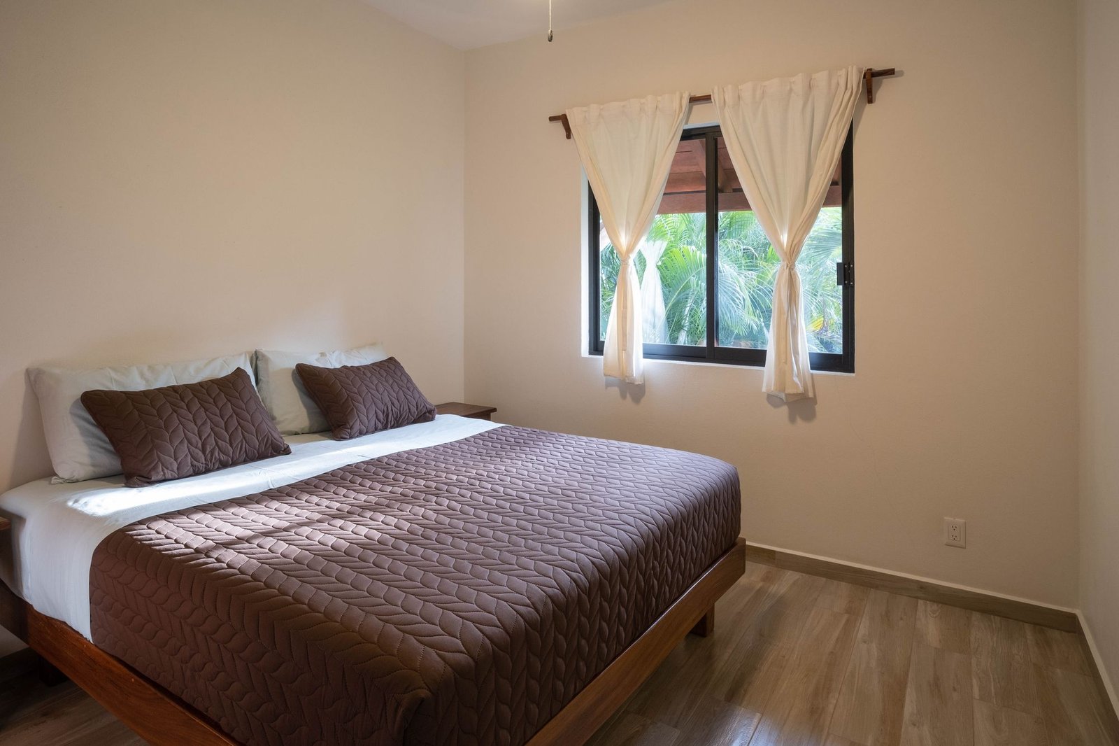 Bedroom at Casa Nisha with king bed and window onto the palms