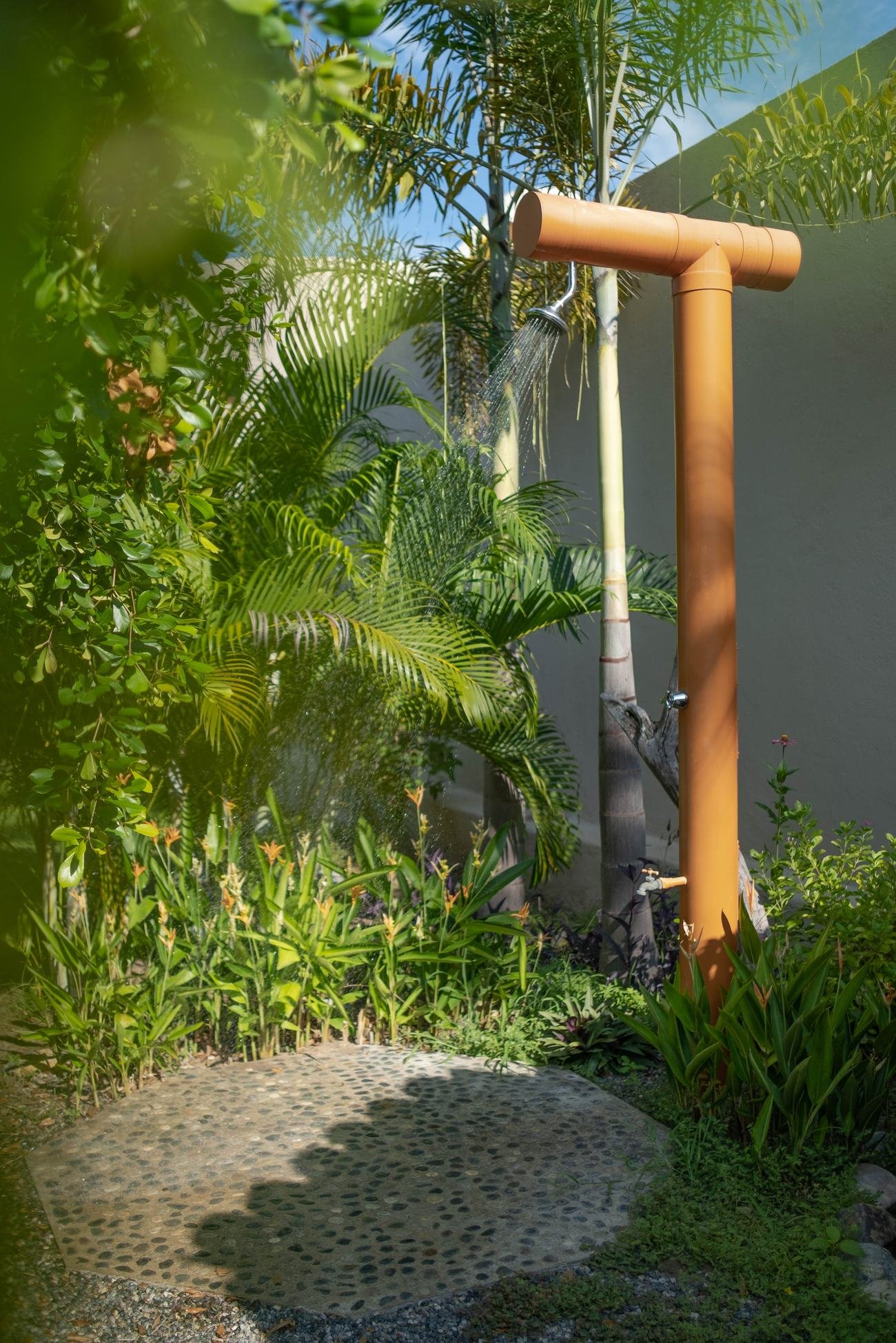 Outdoor garden shower at Casa Nisha surrounded by palms and heliconias