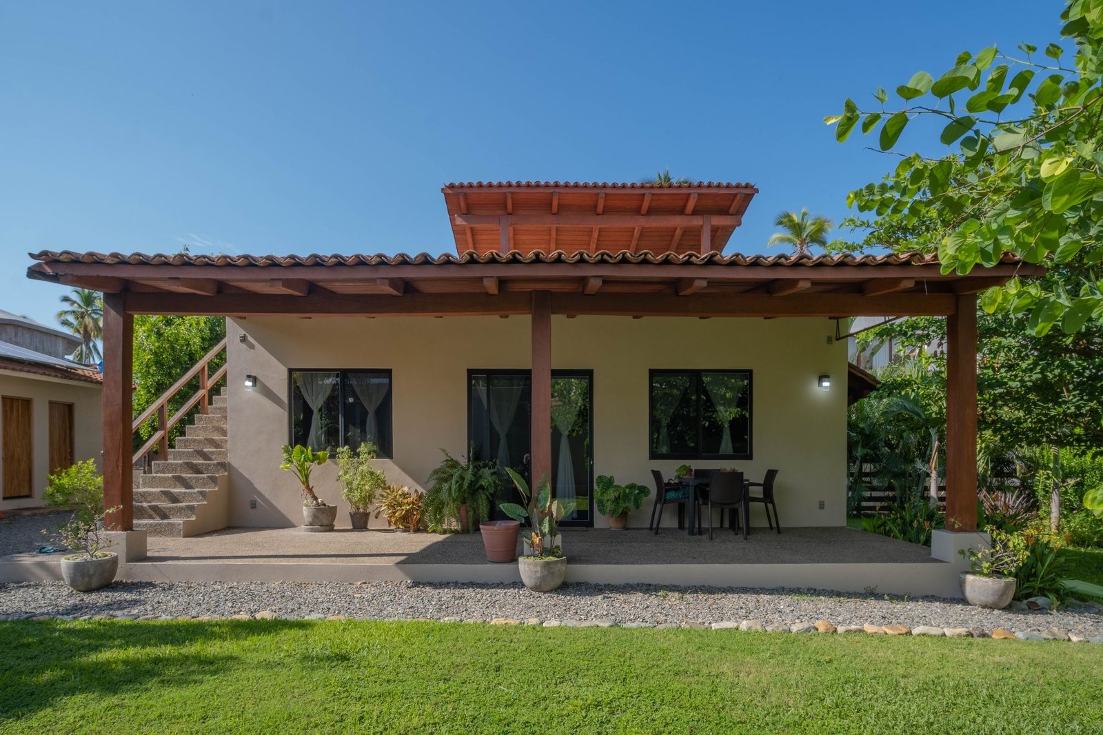Covered terrace of Casa Nisha with dining table, facing the private lawn and tropical garden